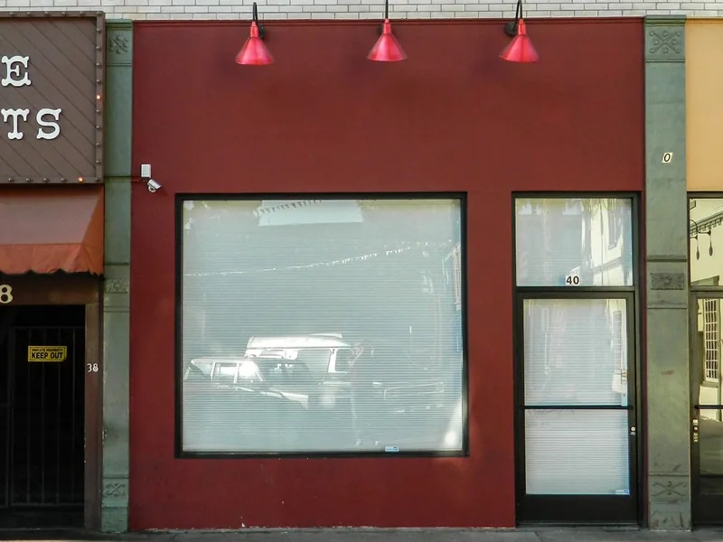 A red storefront with a large display window and a glass entry door