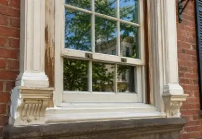 An old wood window with carved trim in a brick wall