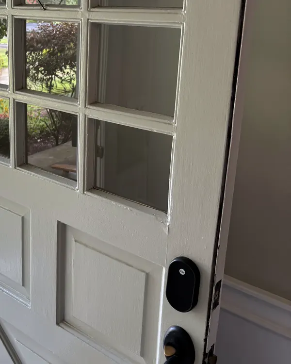 A white entry door with glass panes and a smart lock