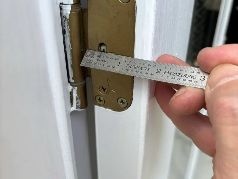 A door hinge being measured with a steel rule