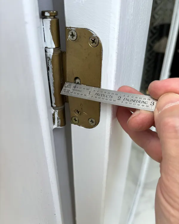 A door hinge being measured with a steel rule