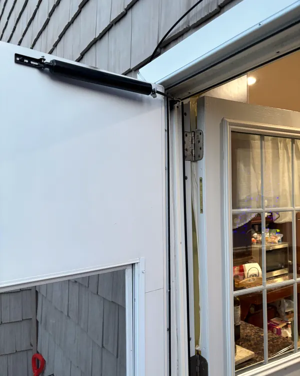 A closer arm at the top of an open storm door