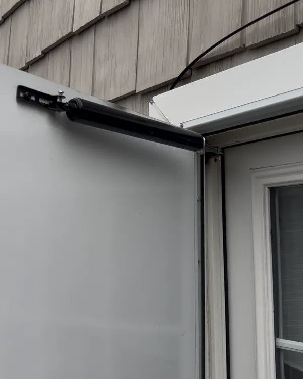 A closer arm on the top rail of a storm door