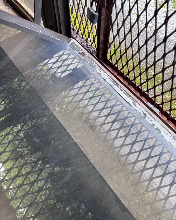 A commercial steel window with a security mesh guard