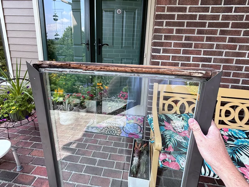 A storm door glass panel held up in front of a brick porch