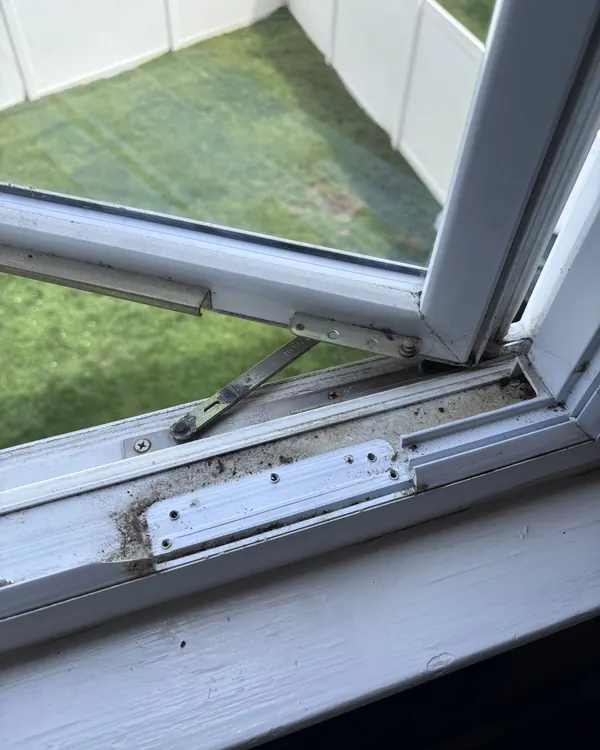 A casement window hinge arm and its track on the sill