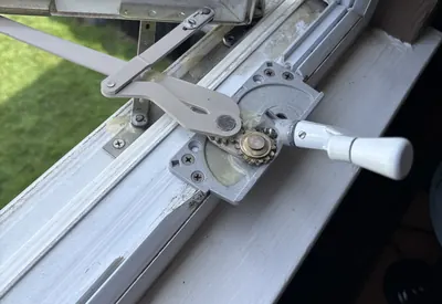 A casement window operator with a white crank handle