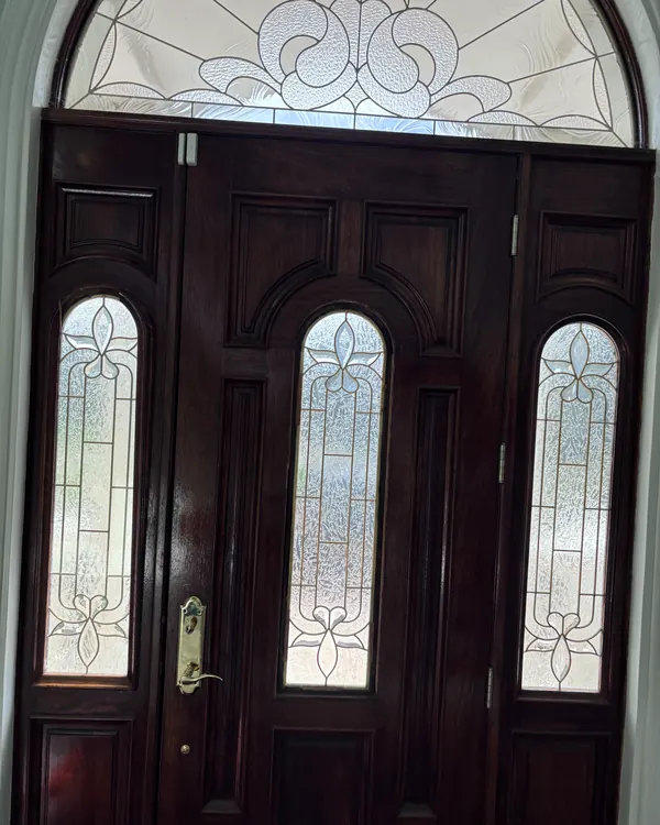 A mahogany double entry door with leaded glass and an arched transom