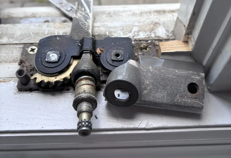 A worn casement window operator gearbox opened up on the sill