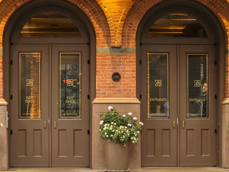 Two arched brick building entrances, each with a pair of entry doors
