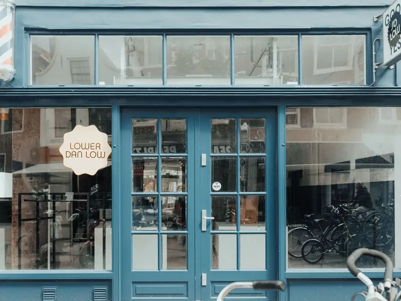 A blue storefront with glass double doors between two display windows