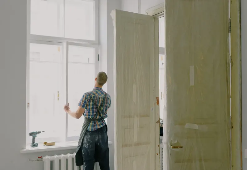 A man adjusting a tall wood door in its frame