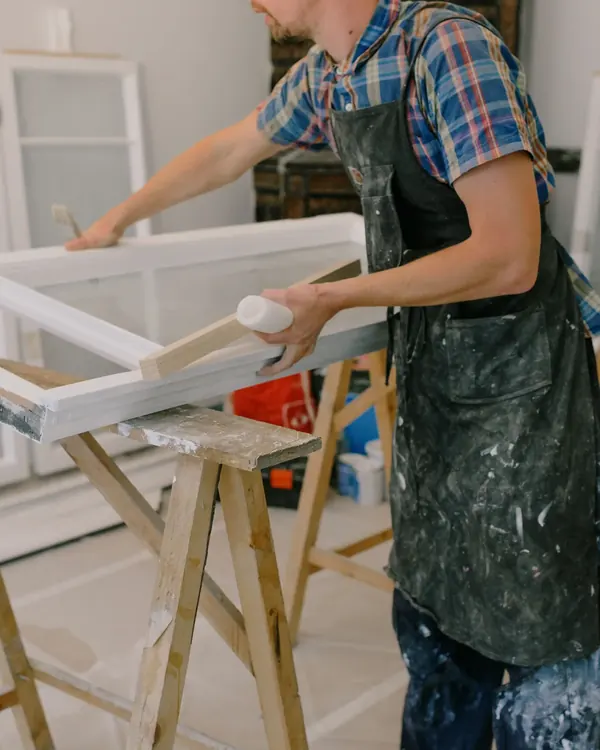 A window sash being glazed on sawhorses in a workshop