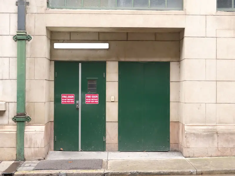 Green steel double doors in the stone front of a commercial building