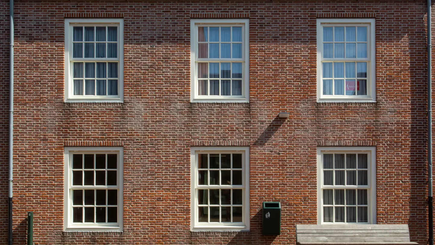 A brick house with rows of double hung windows