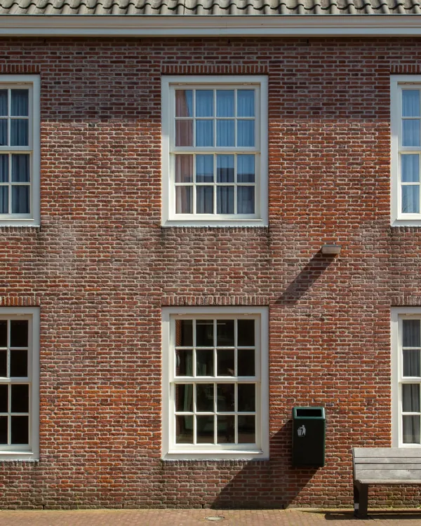A brick house with rows of double hung windows