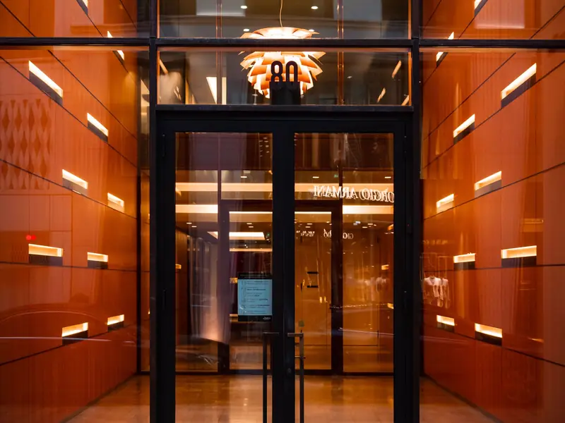 Glass entrance doors into a lit office building lobby