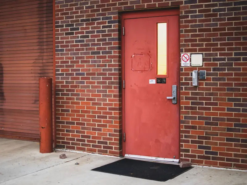 A red steel commercial door in a brick wall