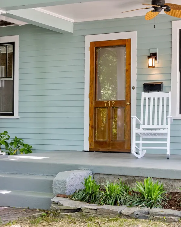 A wood front door with a full glass storm door on the porch of a house
