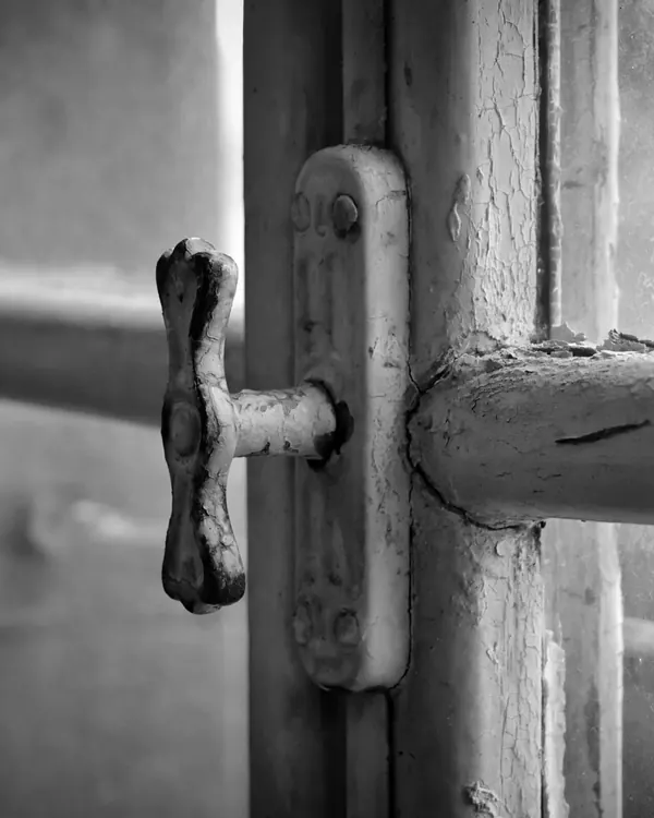 An old metal latch on a wood window
