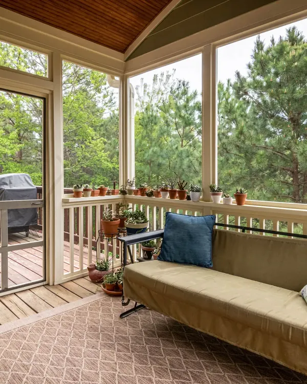 A screened porch with a sofa, looking out to the trees