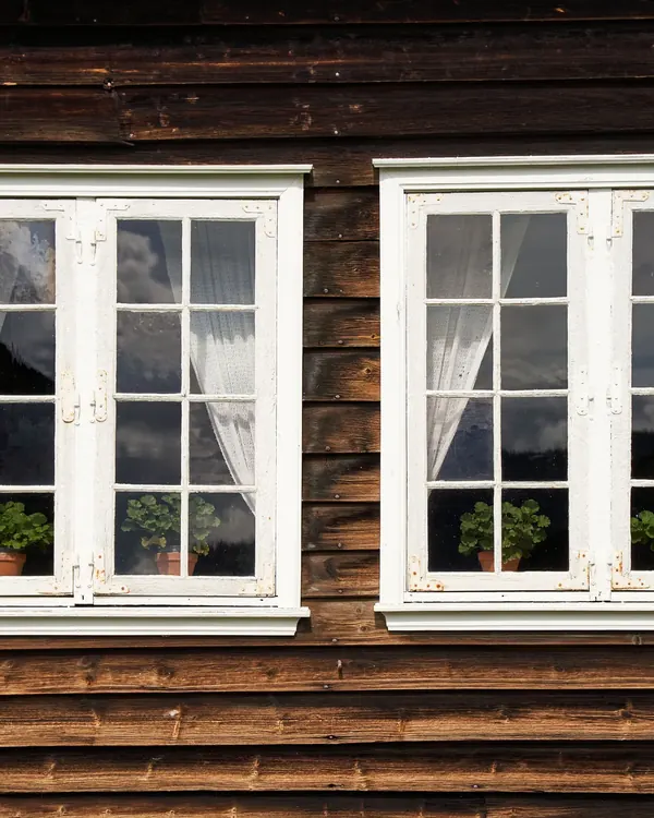 Two white divided pane windows in a dark wood wall